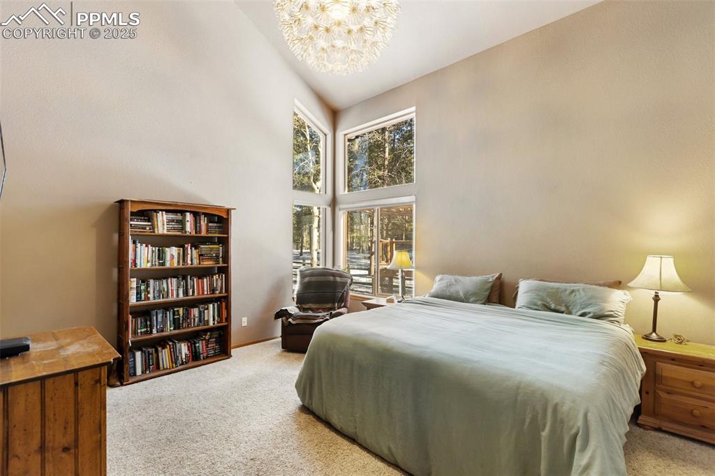 747 Pinon Ridge Drive Woodland Park, CO 80863 - Photo 11 of 32 a bedroom with a bed a dresser and a large window