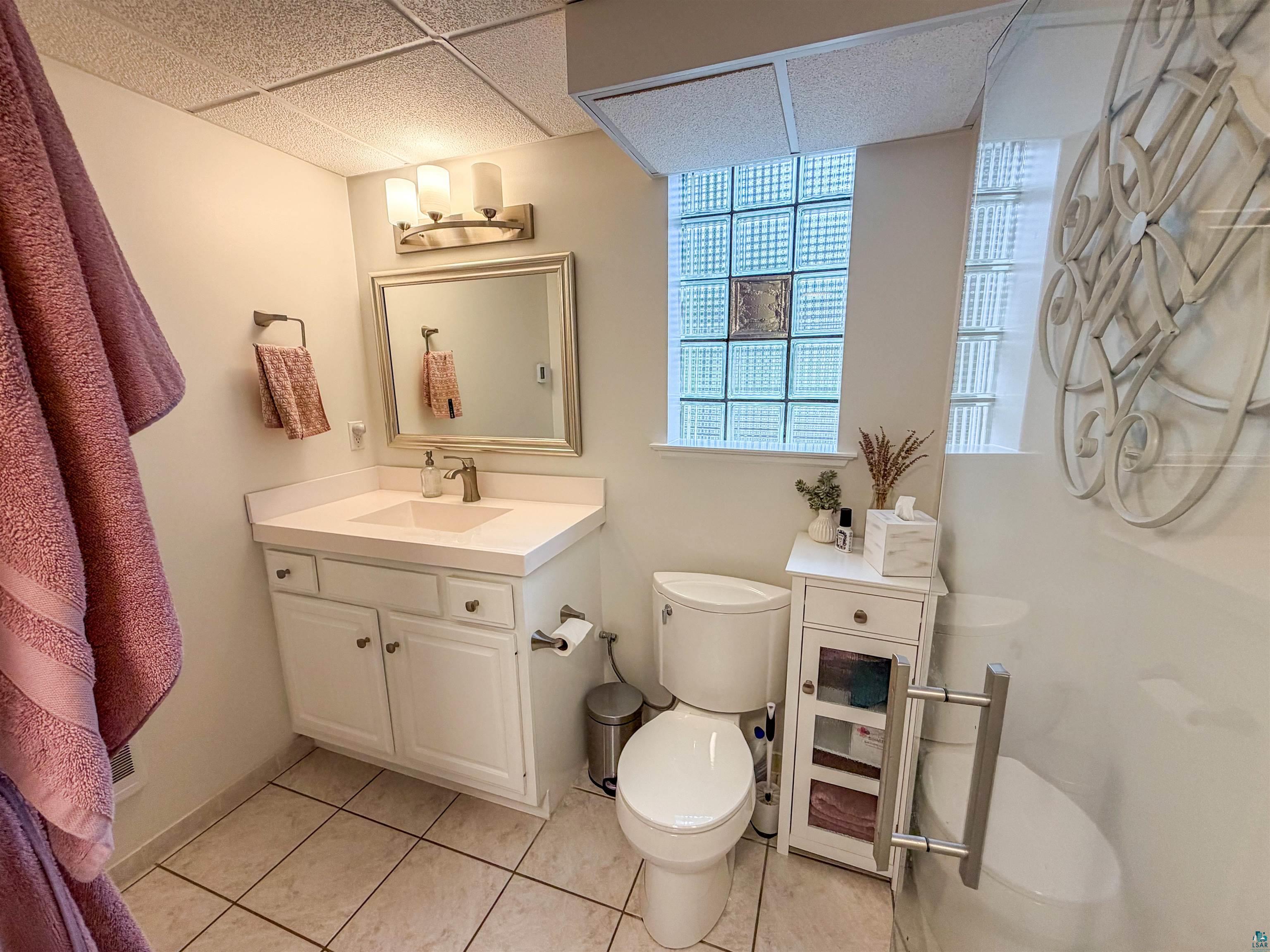 3704 Greysolon Road Duluth, MN 55804 - Photo 30 of 51 Bathroom featuring a white vanity with integrated sink, a framed mirror, and a three-light fixture