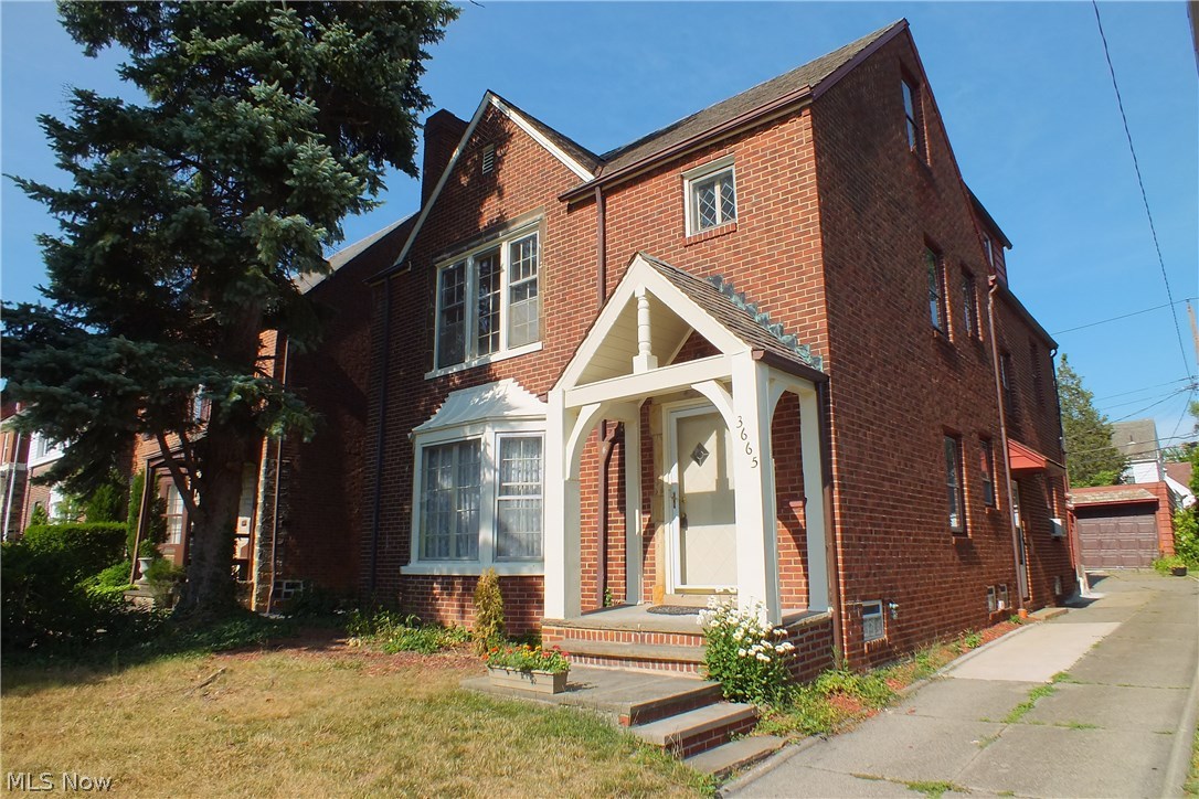 A handsome, solid brick home with concrete driveway leading to the 3-car garage at rear