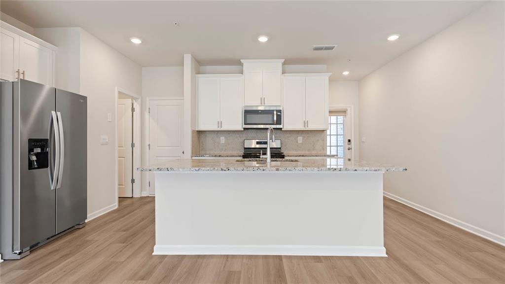 1629 Flint River Place Southeast Smyrna, GA 30126 - Photo 2 of 27 a kitchen with stainless steel appliances granite countertop a refrigerator a sink a stove a microwave and white cabinets with wooden floor