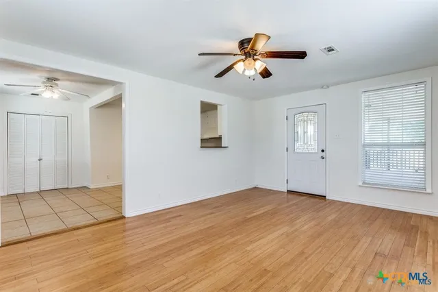 a view of an empty room with wooden floor and a window