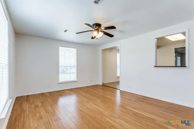 a view of an empty room with window and wooden floor