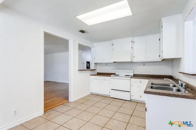 a kitchen with granite countertop white cabinets and white appliances