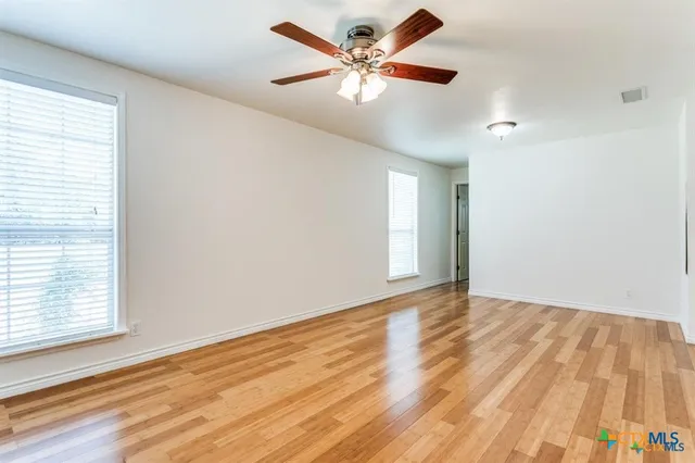 an empty room with wooden floor and windows