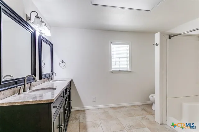 a bathroom with a sink a toilet and a mirror