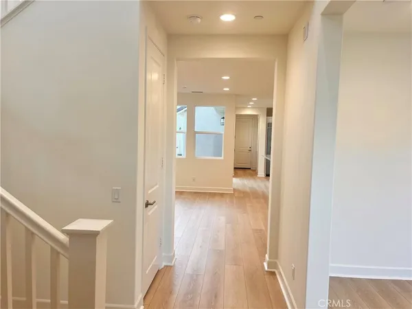 a view of a hallway with wooden floor and a bathroom