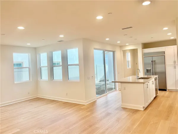 a large kitchen with stainless steel appliances kitchen island a large counter top and a wooden floor