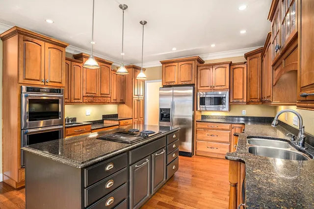 a kitchen with stainless steel appliances granite countertop a stove a sink and a refrigerator