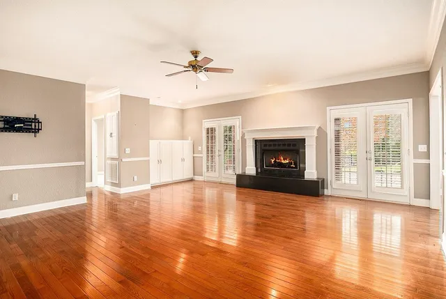 a view of an empty room with wooden floor and a fireplace