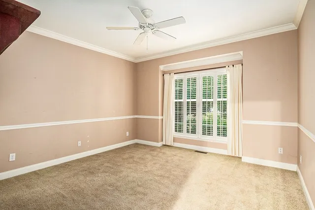 an empty room with chandelier fan and windows