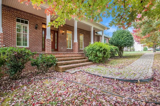 a view of a house with a yard and large tree