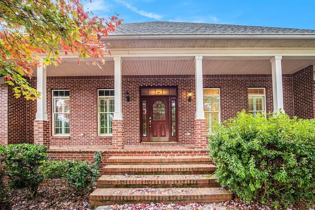 a front view of a house with potted plants and large windows