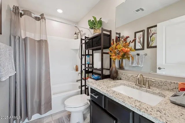 a bathroom with a granite countertop sink a toilet and shower