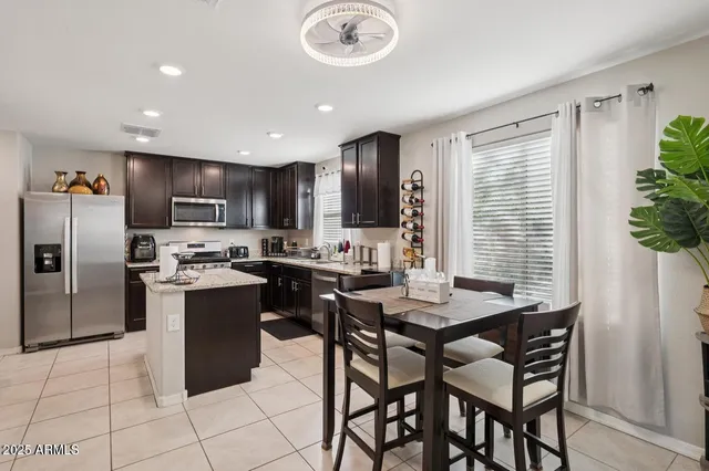 a kitchen with granite countertop a table chairs microwave and refrigerator