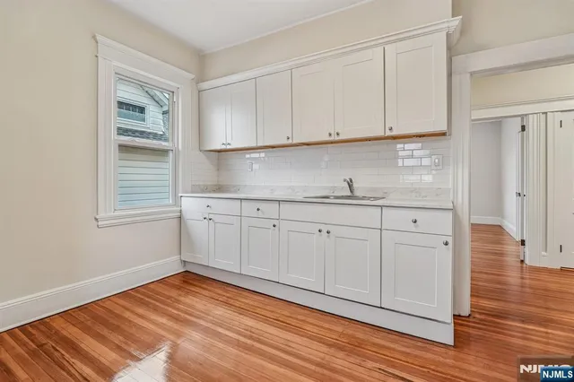 a view of a kitchen with white cabinets and wooden floor