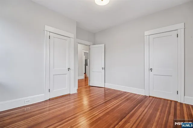 a view of an empty room with wooden floor and closet