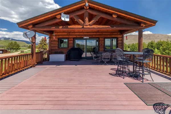 a view of a patio with a table and chairs under an umbrella with a barbeque