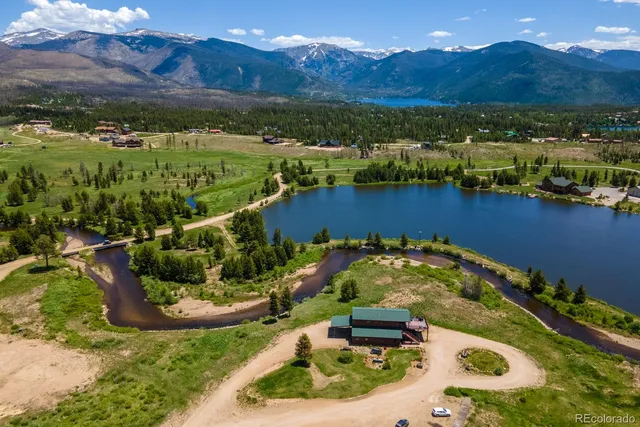 a view of a lake with lawn chairs and large trees