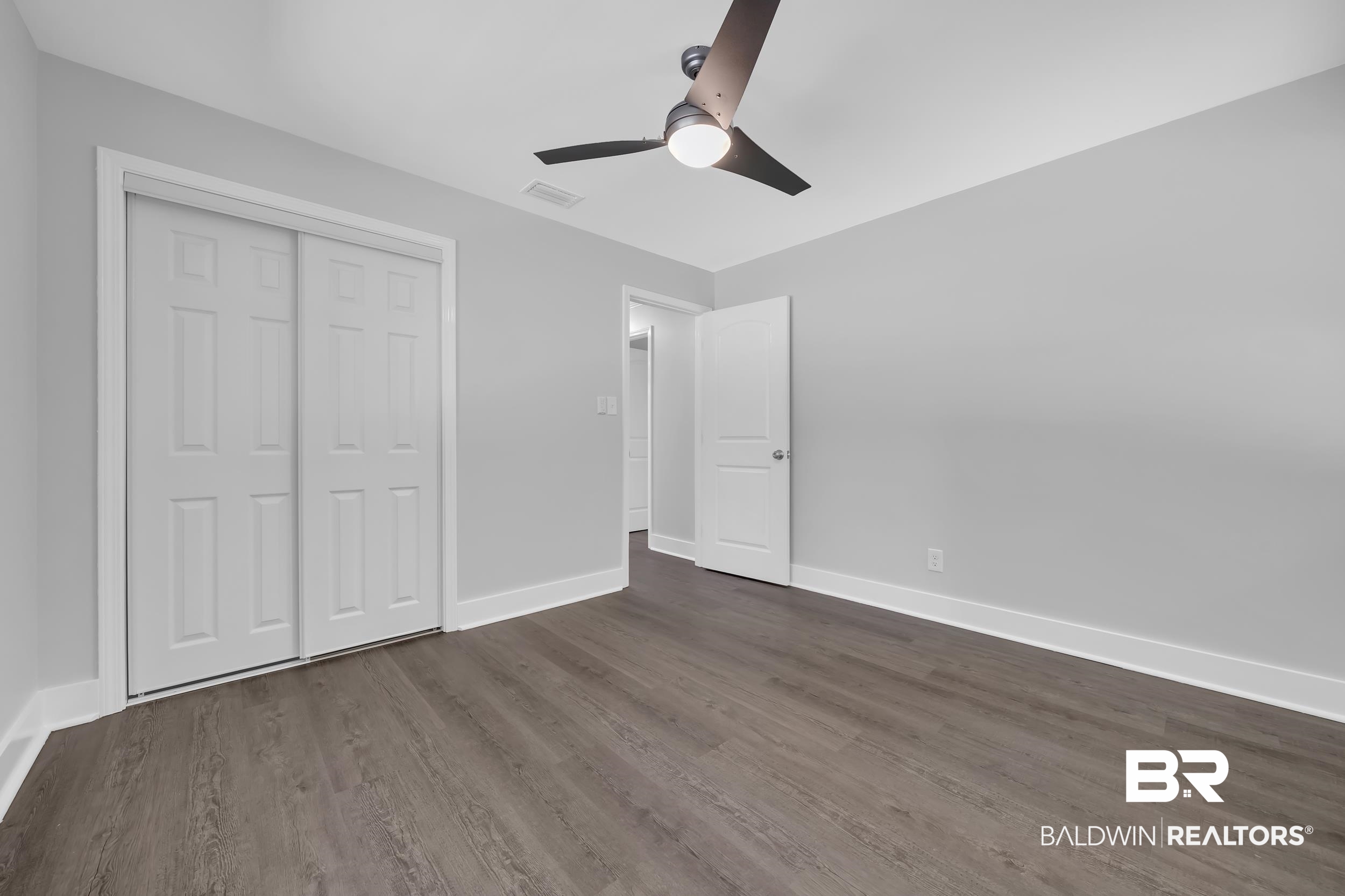 2712 Shelton Beach Rd Extension Mobile, AL 36613 - Photo 17 of 24 Spacious room featuring wood-finish flooring, light gray wall paint, and white trim