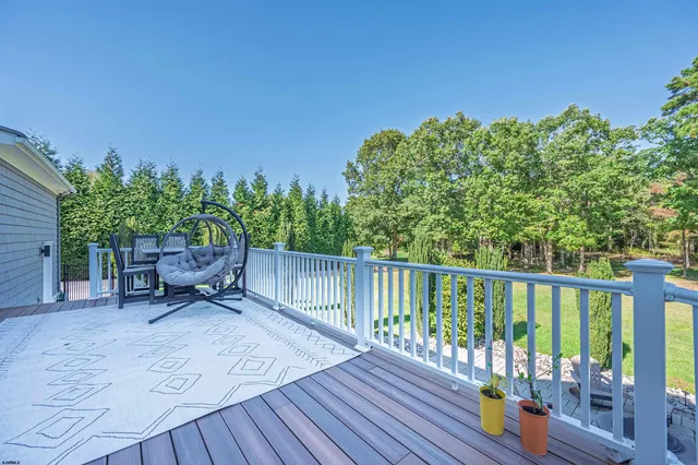 a roof deck with table and chairs and potted plants with wooden floor and fence