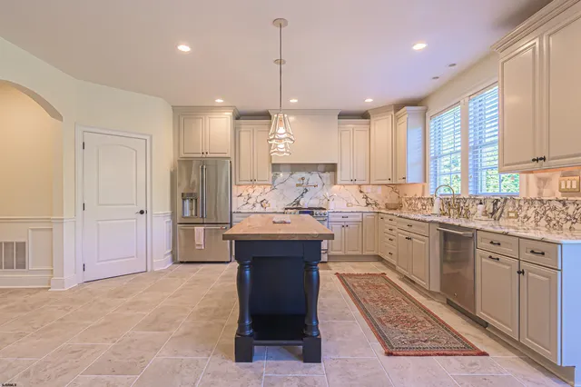 a large kitchen with a large counter top a sink stainless steel appliances and cabinets