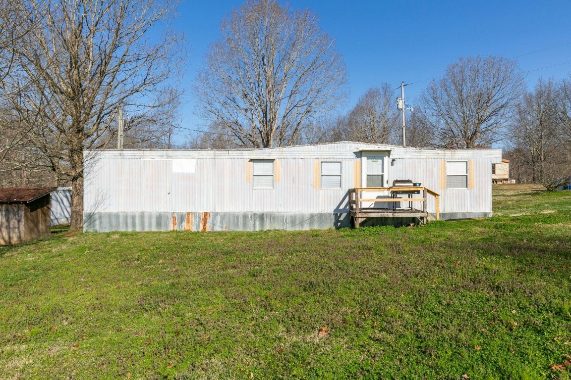 9812 Rocky Point Road Bon Aqua, TN 37025 - Photo 6 of 48 a view of a white house with a big yard and large trees