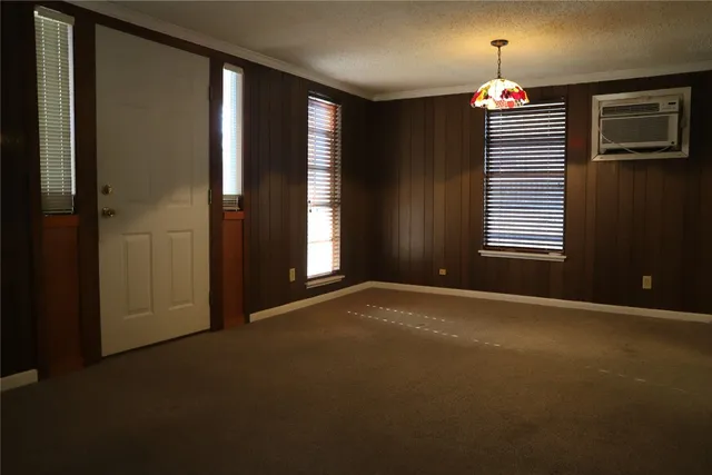 en empty room with windows and chandelier