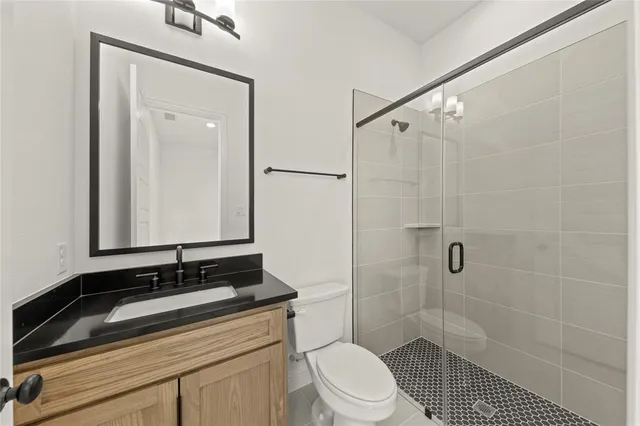 a bathroom with a sink a toilet a mirror and shower
