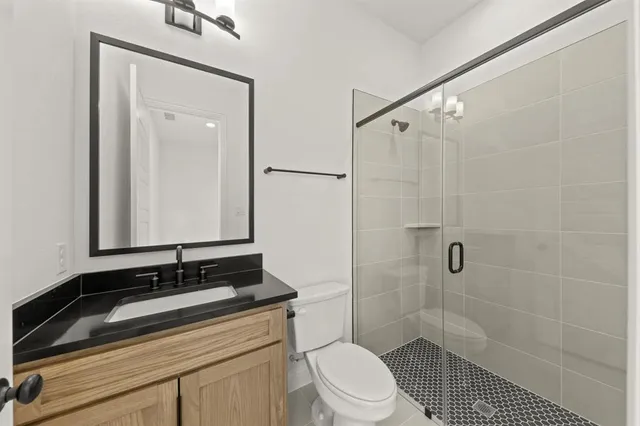 a bathroom with a sink a toilet a mirror and shower