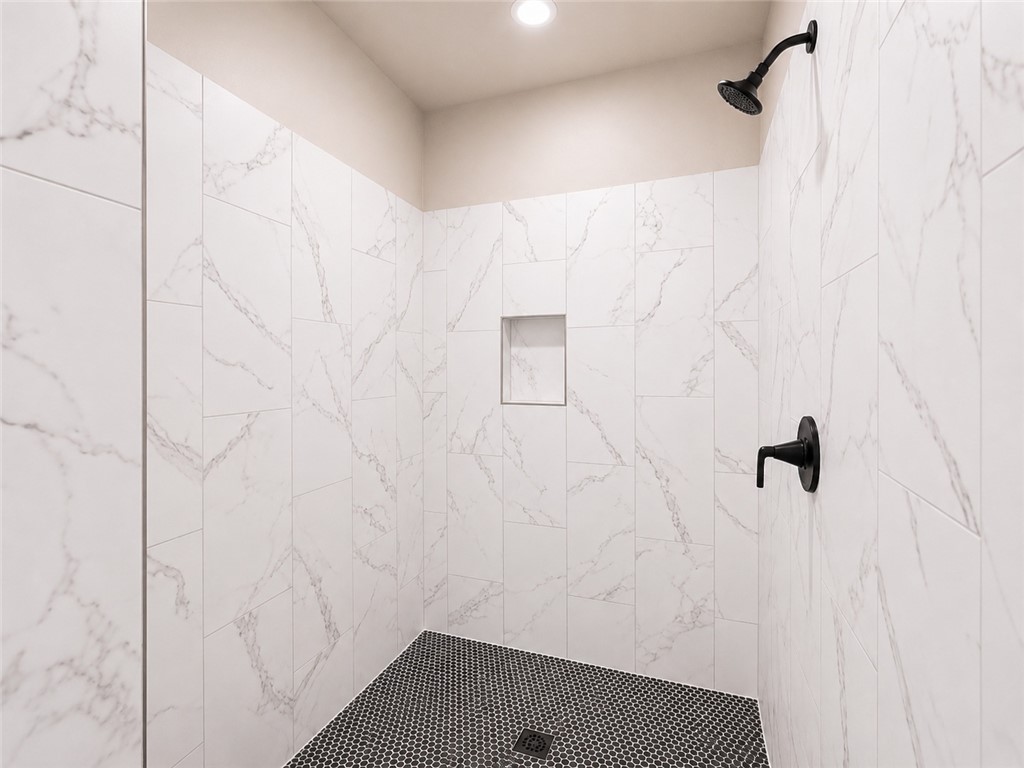 328 Point Road Westminster, SC 29693 - Photo 11 of 24 A striking walk-in shower features large format marble-look tile and a dark hexagon mosaic floor.