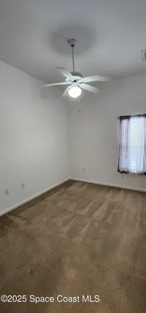 a view of an empty room with a chandelier fan