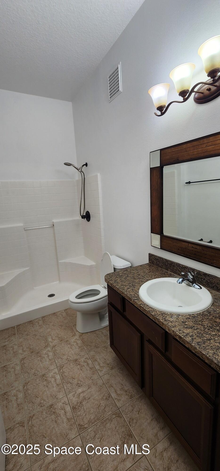 4076 Meander Place, Unit 103 Rockledge, FL 32955 - Photo 19 of 24 a bathroom with a granite countertop sink a toilet and a mirror