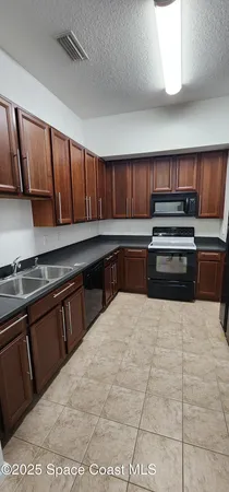 a kitchen with granite countertop a refrigerator stove and cabinets