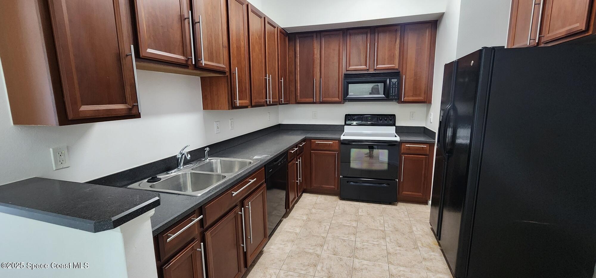 4076 Meander Place, Unit 103 Rockledge, FL 32955 - Photo 7 of 24 a kitchen with granite countertop a refrigerator stove and cabinets