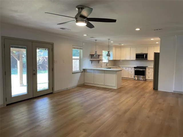 an open kitchen with kitchen island wooden floors and stainless steel appliances