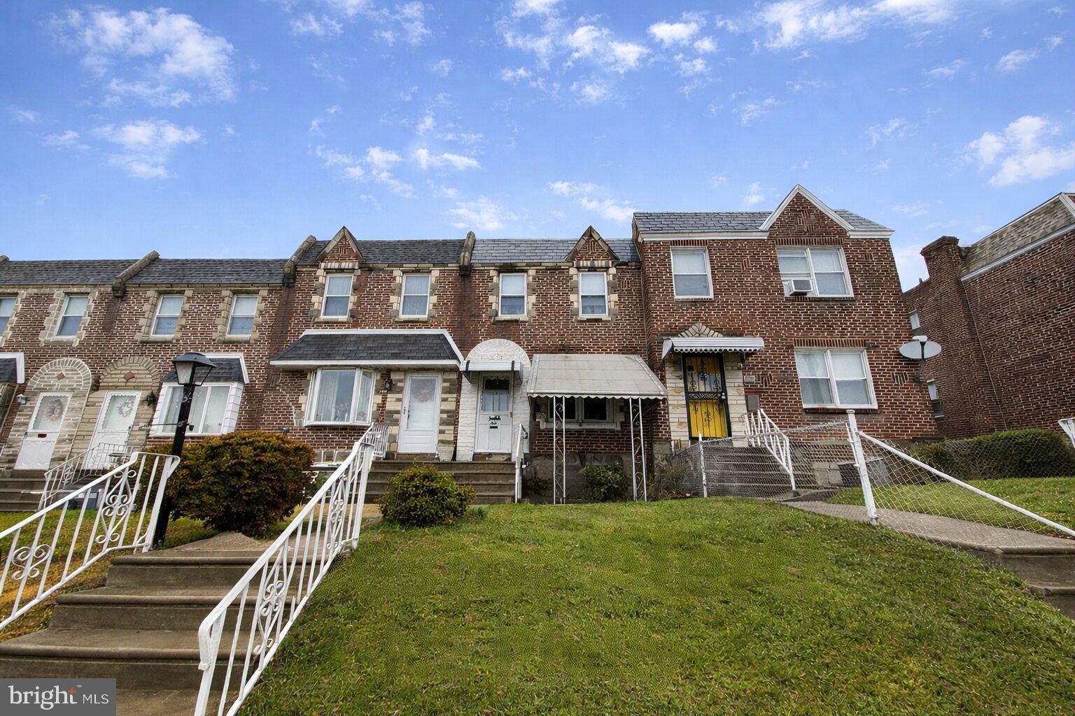 6628 Erdrick Street Philadelphia, PA 19135 - Photo 1 of 4 Charming brick townhomes under a blue sky.