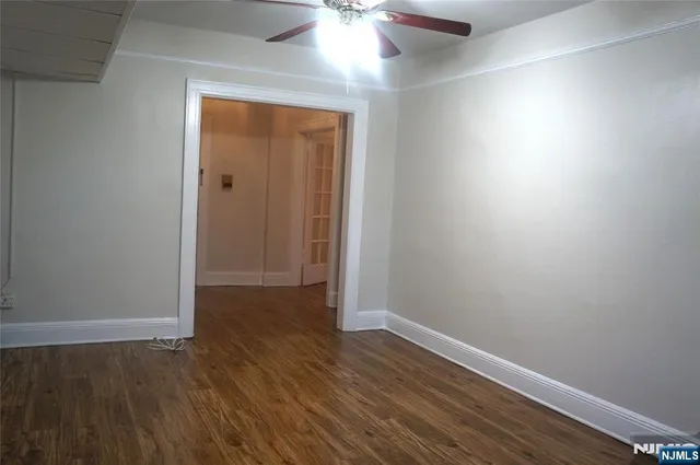 an empty room with wooden floor and a ceiling fan