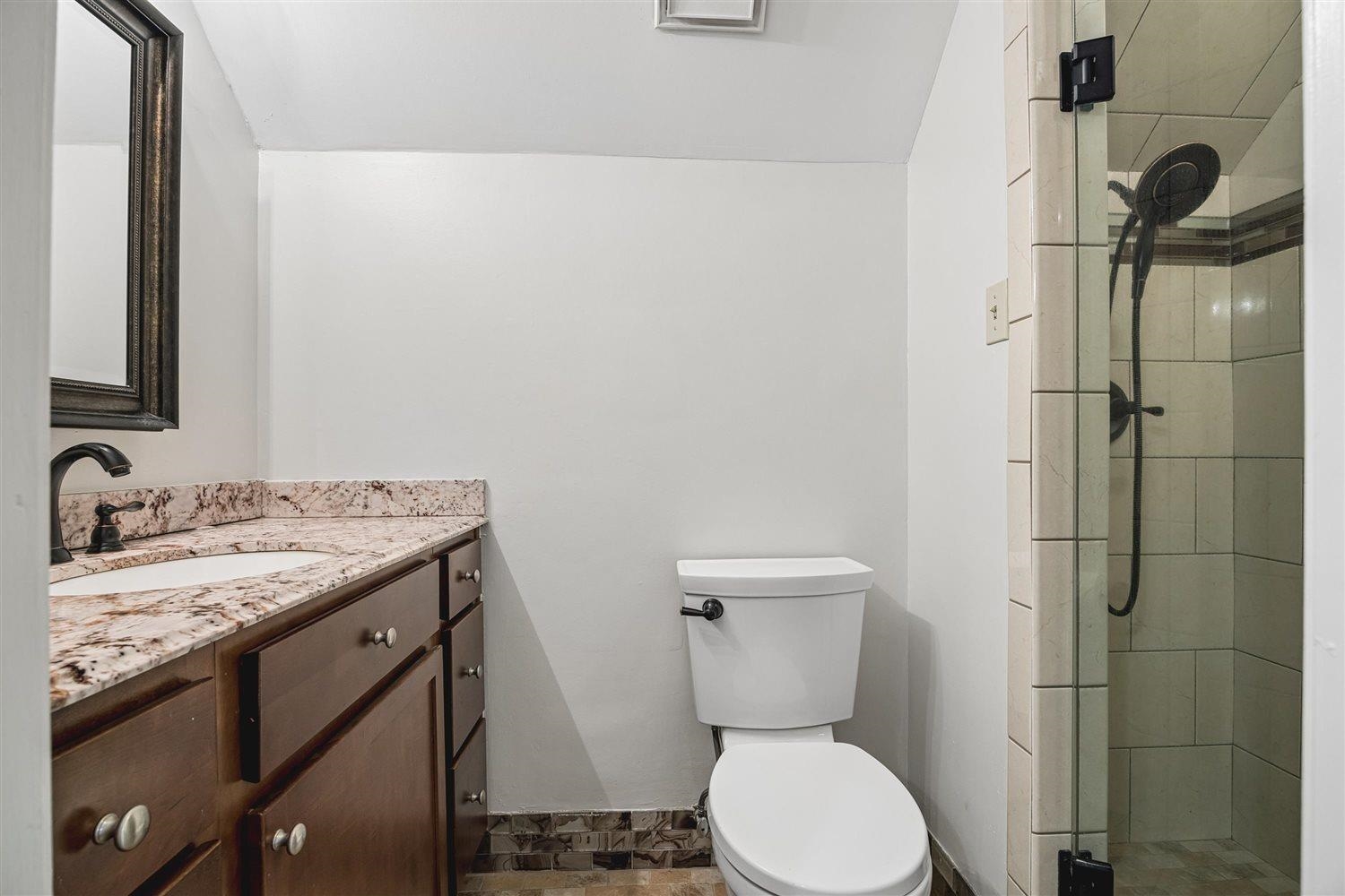 8970 Farmoor Road Germantown, TN 38139 - Photo 23 of 35 Bathroom featuring a dark wood-finish vanity with a light-colored countertop, an undermount sink, a bronze-finish faucet, and a framed mirror
