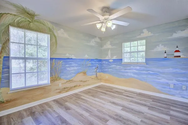 en empty room with wooden floor and ceiling fan