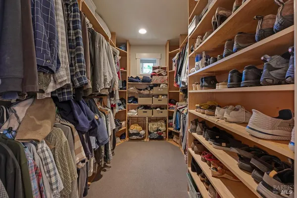 a view of walk in closet with clothes and shoes