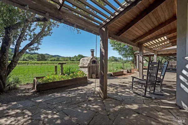 a view of a patio with table and chairs potted plants and a large tree