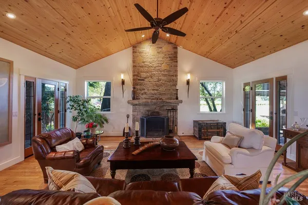 a living room with furniture a fireplace and a dining table with wooden floor