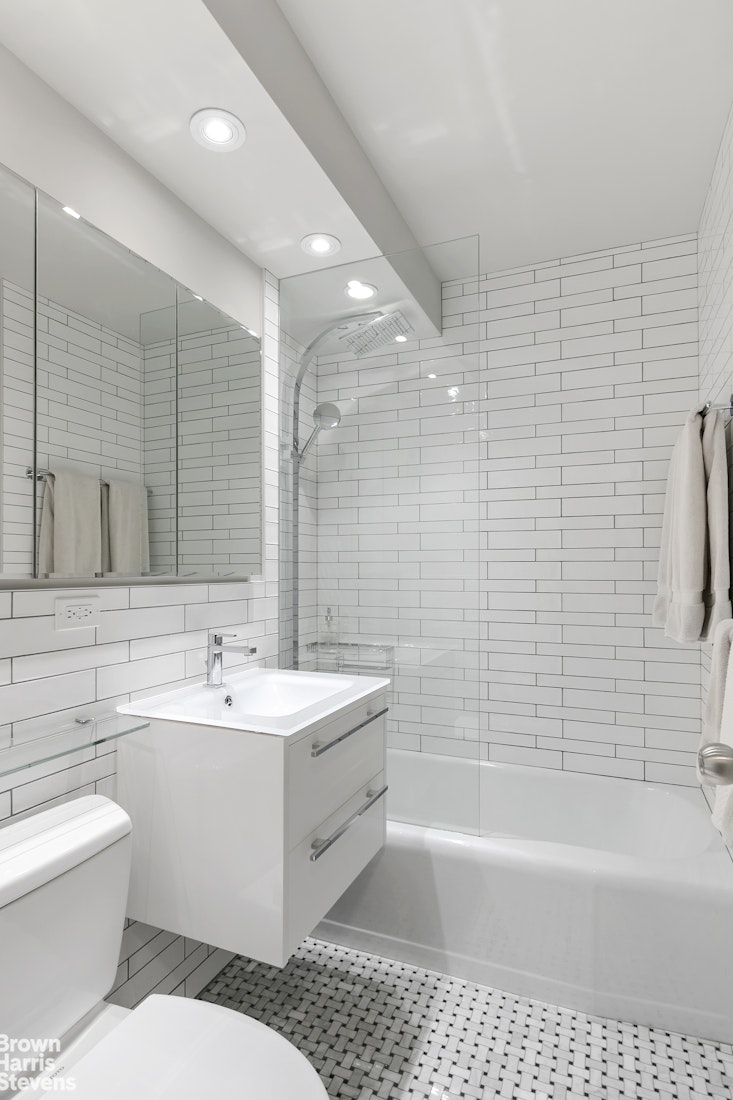 357 East 57th Street, Unit 11E Manhattan, NY 10022 - Photo 5 of 7 a bathroom with a bathtub a sink a toilet a mirror and shower