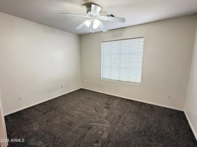 an empty room with a window and a ceiling fan