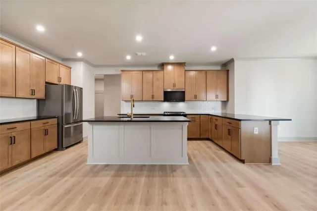 a kitchen with stainless steel appliances granite countertop a refrigerator a sink dishwasher a stove and oven with wooden floor