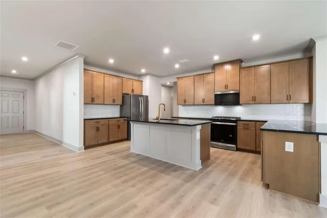 a large kitchen with stainless steel appliances granite countertop a large counter top a sink and a stove