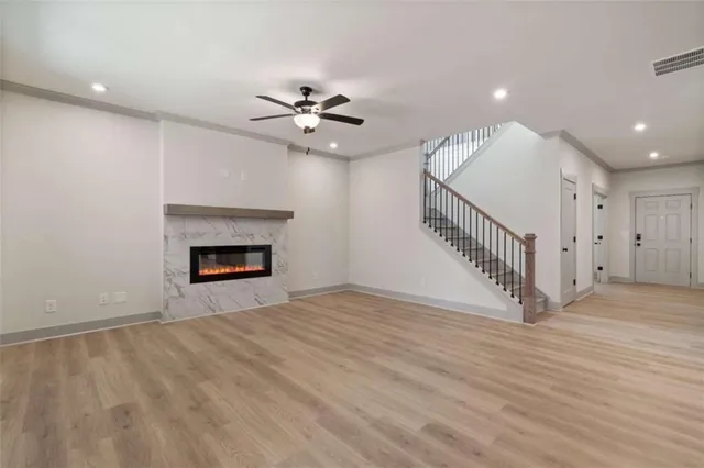 a view of an empty room with wooden floor ceiling fan and fireplace