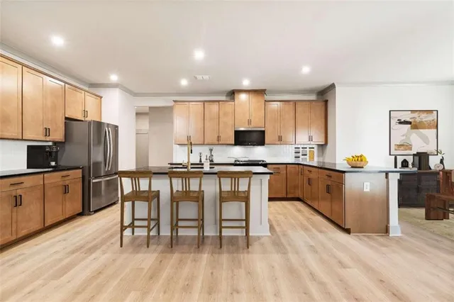 a kitchen with stainless steel appliances granite countertop a refrigerator a stove top oven a sink dishwasher and white cabinets with wooden floor