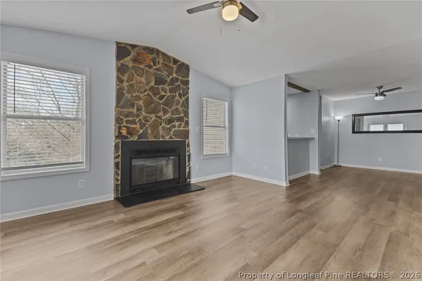an empty room with windows fire place and wooden floor