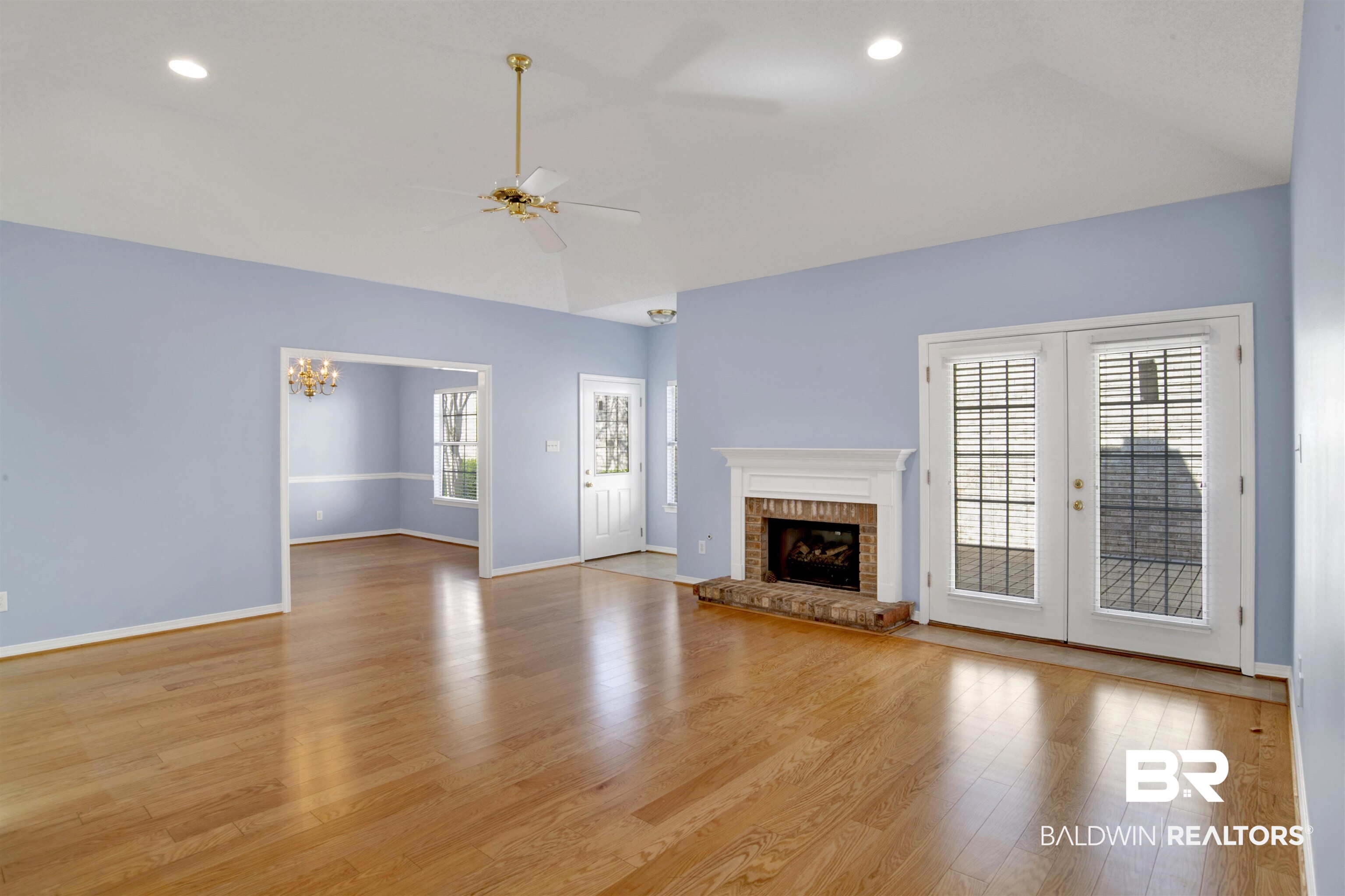 125 Woodruff Court Mobile, AL 36608 - Photo 3 of 27 Unfurnished living room with ceiling fan with notable chandelier, light hardwood / wood-style floors, vaulted ceiling, and a fireplace